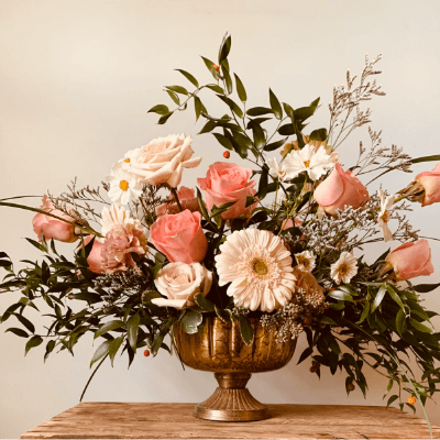 A pink and white arrangement in a bronze vase.