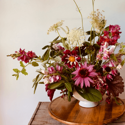 A pink and white flower arrangement in a white vase.